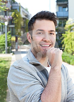 Attractive hispanic guy on outdoors laughing at camera