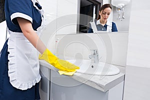 Attractive housekeeper servicing a bathroom