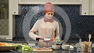 Attractive housewife in hijab put cut fresh vegetables in deep plates preparing halal food