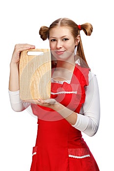 Attractive housewife in red apron with funny ponytails and wooden rectangular cutting board