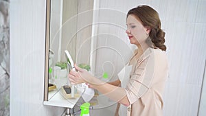 an attractive housewife washes the sink and bathroom mirror