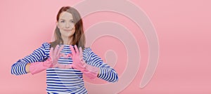 Attractive housewife woman wear rubber cleaning gloves and casual blue striped sweater makes heart gesture over cest, body