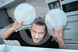 attractive hungry young man on modern kitchen with empty plate, fork and knife