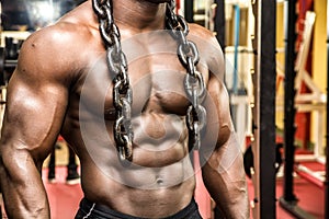 Attractive hunky black male bodybuilder posing with iron chains