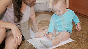 Attractive kid draws a pencil on the floor with mom at home. The boy is smiling and playing with his mother. The concept