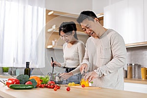 Attractive korean man and woman cooking together at home