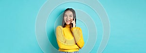 Attractive korean woman in yellow sweater, having conversation and smiling, talking on mobile phone, looking left at