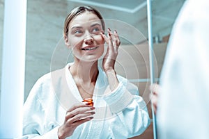 Attractive lady in white robe enjoying skincare routine