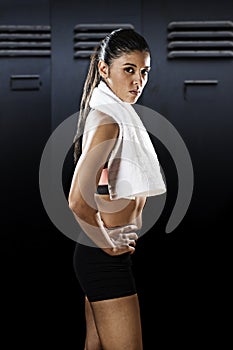 Attractive latin sport woman posing with towel in fierce and badass face expression