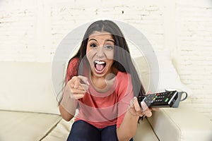 Attractive latin woman at home sofa couch laughing and smiling happy watching television