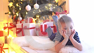 Attractive little boy unwrapping Christmas gifts. Kid opening New Year presents at home.