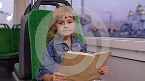 Attractive little child girl kid sitting at empty subway train, reading interesting book