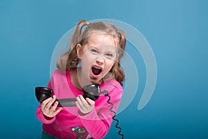 Attractive little cute girl in pink shirt with monkey and blue trousers talks a phone