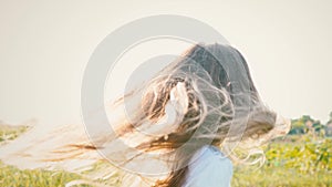 An attractive little girl with long flowing hair twists her head in different directions, the wind develops long hair of