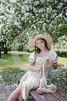 An attractive long-haired woman walks in the spring in the park of blooming apple trees.