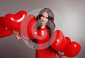 Attractive love portrait brunette woman in red with heart balloons isolated on gray studio background. Valentine day. Birthday pa