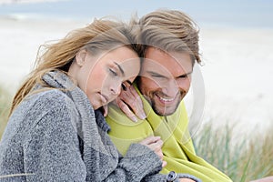 The attractive lovely woman and man sit in the sand dune of a beach relaxing - autumn, beach, sea