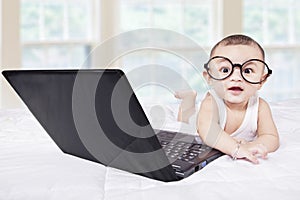 Attractive male baby with laptop on bed