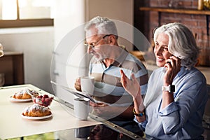 Attractive male and female pensioners having breakfast in the kitchen