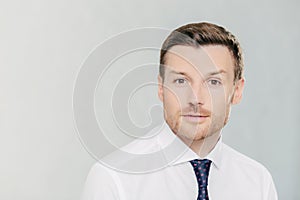 Attractive male freelancer works remotely, wears elegant white shirt with tie. Isolated on white studio wall. People, facial