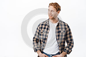 Attractive male model with ginger hair and bristle, turn head aside, looking at advertisement with satisfied face, nod