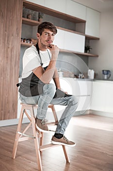 Attractive man with an apple sitting in a home kitchen