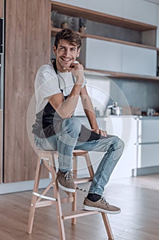 attractive man with an apple sitting in a home kitchen