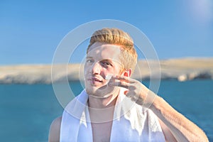 Attractive man applying protective sun cream (solar cream, sunscreen). Young handsome caucasian male model.