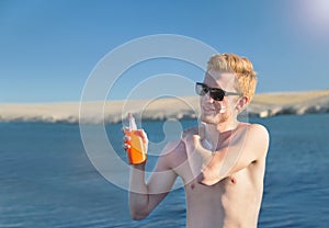 Attractive man applying protective suncream.