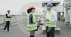 Attractive man architect with a good looking African lady engineer speaking together on the rooftop of construction site