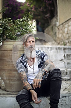 Attractive man with a beard and tattoos is sitting on the stairways in the old city of athens photo