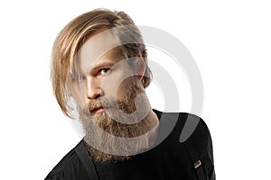 The attractive man the blonde with long hair of the European appearance with a beard in a black t-shirt and black trousers on a