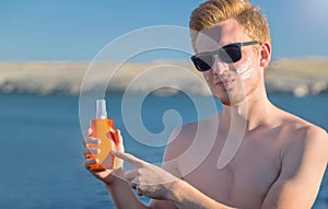 Attractive man with botle of protective sun cream & x28;solar cream, sunscreen& x29;. Young handsome caucasian male model.