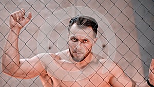 An attractive man boxer standing behind the net in the gym