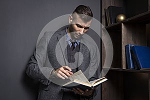 Attractive man in a business suit reads a book. The lawyer holds the directory in his office. Learning man with book