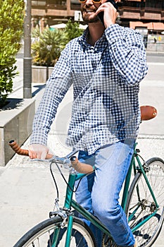 Attractive man calling with his mobile phone on a fixed gear bicycle in the street