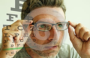 Attractive man checking vision trying glasses at optometrist . guy on his 40s during optical examination testing spectacles for