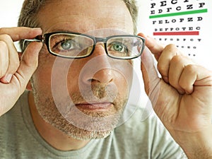 Attractive man checking vision trying glasses at optometrist . guy on his 40s during optical examination testing spectacles for