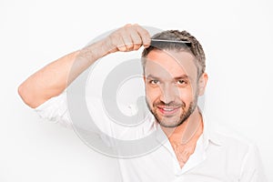 Attractive man combing his hair on white background