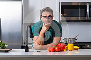 Attractive man cooking in modern kitchen. Handsome man cooking at home preparing salad in kitchen. Casual man preparing