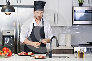 Attractive man cooking in modern kitchen. Handsome man cooking at home preparing salad in kitchen. Casual man preparing