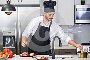 Attractive man cooking in modern kitchen. Handsome man cooking at home preparing salad in kitchen. Casual man preparing