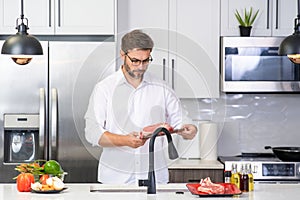 Attractive man cooking in modern kitchen. Handsome man cooking at home preparing salad in kitchen. Casual man preparing
