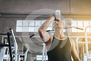 Attractive man drinking water in gym,Men break and relex after workout photo