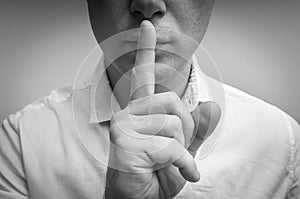 Attractive man with finger on lips making silence gesture