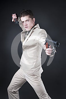 Attractive man with a gun wearing a white suit