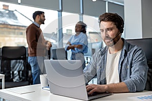 Attractive man in headset working on laptop