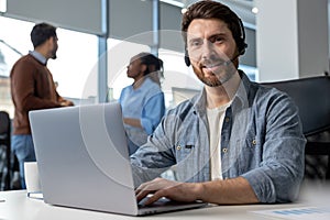 Attractive man in headset working on laptop