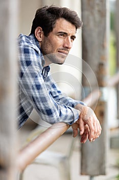 Attractive man leaning on post by barn