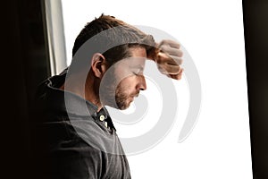 Attractive man leaning on window suffering emotional crisis and depression